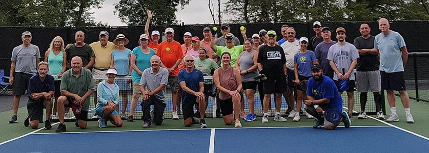 group of people posing for picture on pickleball court